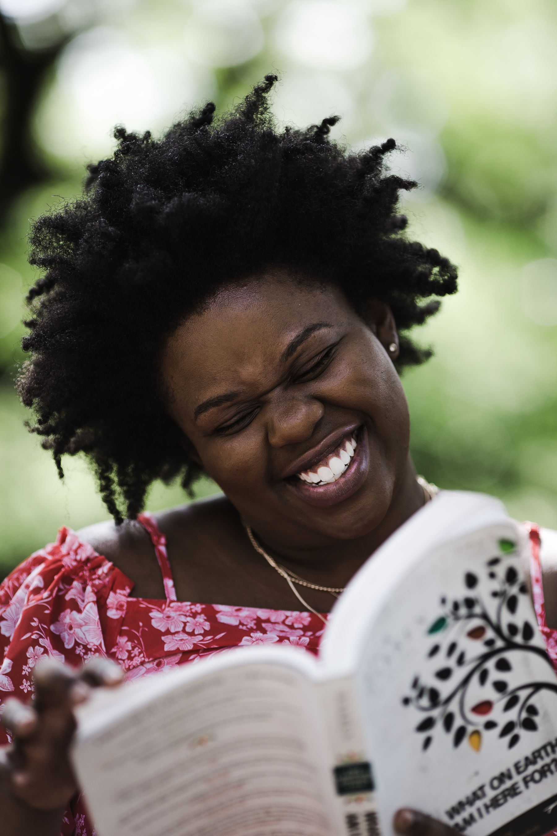 A woman smiling while reading outdoors
